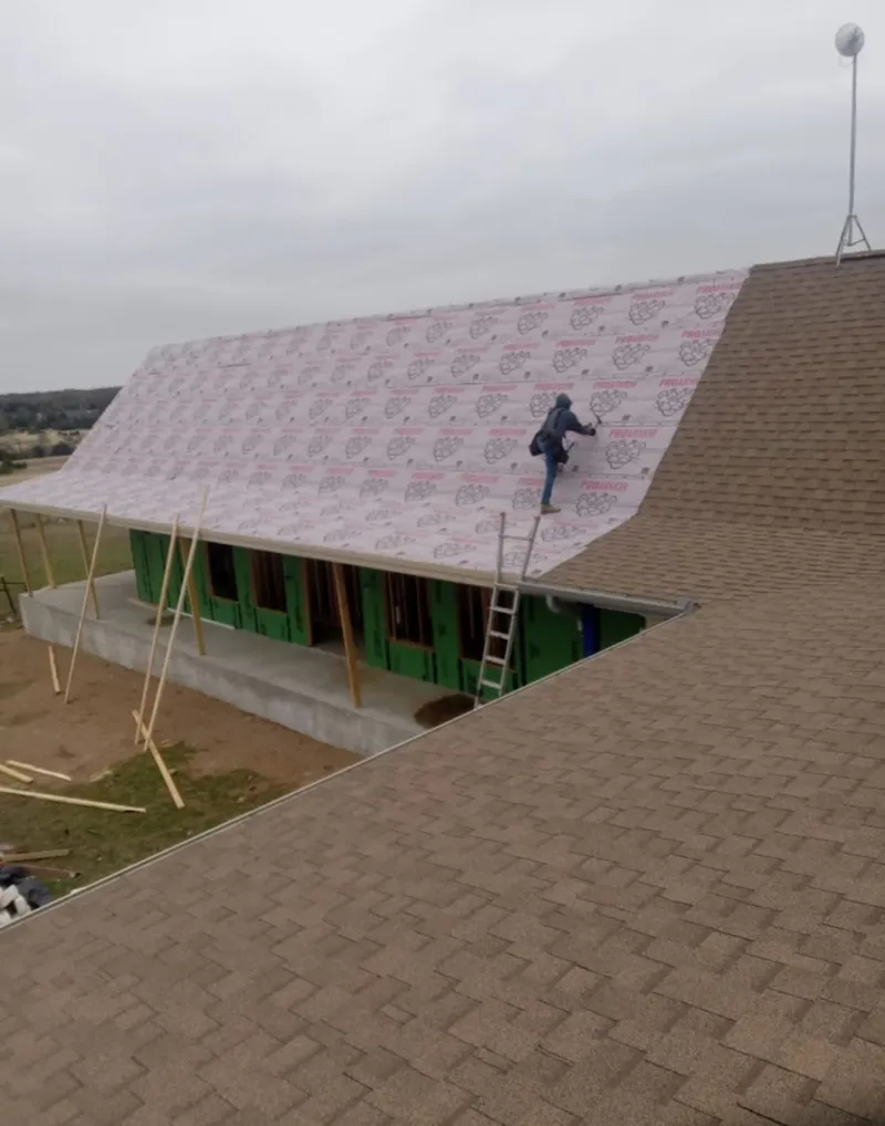 Worker preparing underlayment for a metal roof installation in Cold Springs
